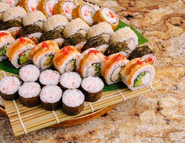 İçinde karides, yengeç ve sebze gibi renkli malzemeler bulunan çeşitli suşi dürümleriyle dolu canlı bir tabak. Özel bir toplantıda ya da özel bir günde paylaşmak için mükemmel..