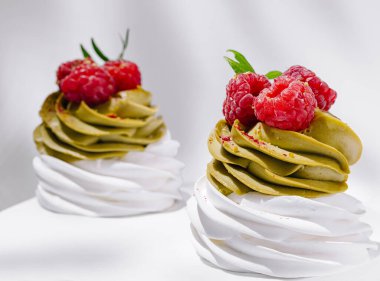 İki güzel kremalı ve taze ahududu ile kaplı beyaz bir yüzeyde oturuyorlar. Hassas girdaplar her durum için mükemmel bir sunum yaratır..