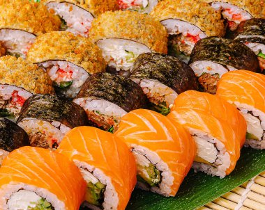 Bu canlı tabakta somon, baharatlı ton balığı ve çıtır çıtır seçenekler de dahil olmak üzere çeşitli suşi ruloları yer alıyor. Düzenleme renkli bileşenleri ve dokuları vurgular.