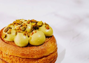 Ağız sulandıran bir hamur işi açık bir yüzeyde, altın-kahverengi bir kabuk içerir. Cömertçe kremalı şam fıstığı dolgulu ve çıtır fındıklı, enfes bir ziyafet sunuyor..