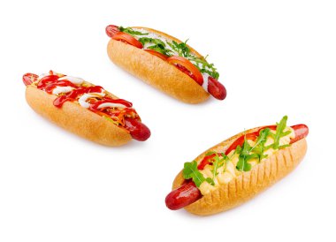 Beyaz arka planda üç sosisli gösteriliyor. İlk sosislinin üstü ketçapla, ikincisinde mayonez ve roka, üçüncüsünde ise domates ve soğan..