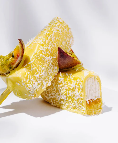 İki canlı sarı donmuş şeker beyaz bir yüzeyde oturuyor. Patatesler hindistan cevizi parçacıklarıyla kaplı ve kremayla dolu. Olgun tutku meyveleriyle kaplanmış taze ve cezbedici görünüyorlar..