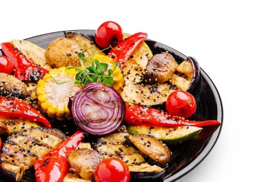 Renkli bir yemekte, kiraz domatesleri ve kırmızı soğanla süslenmiş kırmızı biber, kabak, mantar ve mısır gibi ızgara sebzeler yer alıyor..