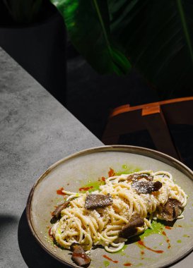 Yer mantarı ve peynirle kaplı bir tabak makarna kırsal bir masada oturur. Sıcak, cezbedici atmosfer yeşillik ve hafif ışıklandırmanın ipuçlarını barındırıyor. Yemek yemek için mükemmel..