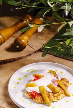 Çok güzel hazırlanmış bir tatlı krema ve çiçeklerle süslenmiş taze meyve parçalarıyla süslenmiş çıtır bir taban sunar. Ortam ahşap elementleri içeriyor, doğal hissi arttırıyor..