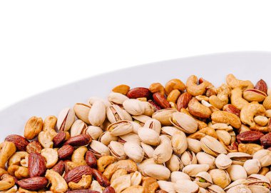 Beyaz bir tabakta fındık çeşitlerinin yakın çekim görüntüsü. Fıstık, fıstık ve fıstık içeriyor, zengin dokularını ve renklerini sergiliyor, atıştırmak ve sağlıklı yemekler için mükemmel..