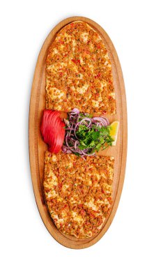 Kıyma ve baharatla kaplı düz ekmek ahşap bir tabakta sunuluyor. Domates, kırmızı soğan ve şifalı otlar gibi taze sebzeler tat vermesi için limon dilimlerine renk katar..