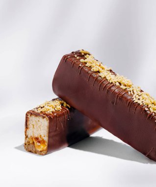 Temiz bir yüzeyde iki çikolata kaplı tatlı gösterilir. Biri bir bütün, diğeri bir ısırık alırken, kremalı dolgu ve fındıklı, davetkar tatlı arzular ortaya çıkıyor..