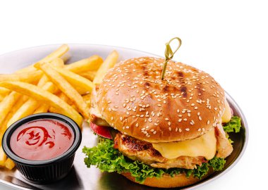 Taze yapılmış bir tavuklu sandviç marul, peynir ve kızarmış patates ve gümüş bir tepside ketçapla eşleştirilmiş susamlı bir çöreğe sahiptir. Lezzetli bir yemek için mükemmel..