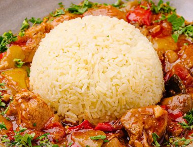 Lezzetli bir yemek, lezzetli bir tavuk ve sebze yahnisi eşliğinde yumuşacık bir pirinç yığını içerir. Taze otlar bu iştah açıcı yemeğe renk ve tat katar..