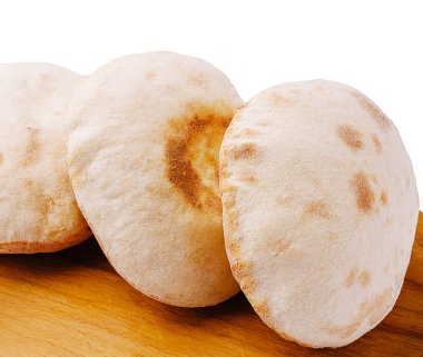 Taze pişmiş pita ekmeği, yumuşak dokusu ve hafif altın noktalarıyla ahşap bir yüzeyde uzanıyor. Çeşitli yemekler ve soslar için mükemmel, bu ekmek harika bir eklenti..