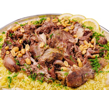 Cömert bir tabakta yumuşak pirinç üzerine katmanlanmış kızarmış et yer alıyor. Taze otlarla süslenmiş, içine biraz fındık serpiştirilmiş ve limon dilimleri eklenmiş..