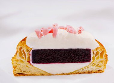 Bu tatlı zengin krema ve canlı böğürtlen katmanıyla dolu yumuşak bir pasta sergiliyor. Tatlı, pembe talaşlarla kaplıdır. Her durum için mükemmeldir..