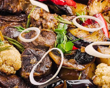 Izgara et, kırmızı biber ve karnabahar da dahil olmak üzere rengarenk sebzelerle kırsal ahşap bir masada servis edilir ve ağız sulandırıcı bir ziyafet yaratır..