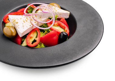 Bu yemek, domates, salatalık ve biberden oluşan, üzerinde peynir ve zeytin bulunan renkli bir taze sebze salatasına sahiptir. Zarif bir siyah tabakta servis edilir..