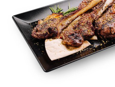 Lezzetli kuzu pirzolaları mükemmel ızgara yapılır ve şık bir siyah tabakta sunulur. Taze otlar bu iştah açıcı yemeğe tat ve aroma ekler, lezzetli bir yemek için idealdir..