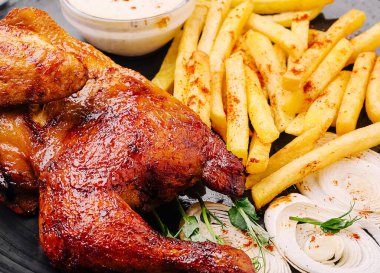 Sulu ızgara tavuk butları kızarmış patates kızartması ve taze soğanın yanında servis edilir. Sos bu lezzetli yemeği güzelleştirir. Tatmin edici bir öğle yemeği veya akşam yemeği için mükemmel olur..