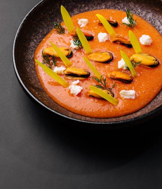 Güzel bir kaplanmış deniz ürünleri tabağı parlak kırmızı bir sos üzerinde midye içerir. Taze yeşil elementler, kremalı parçalar ve otlar yemeğe renk ve doku ekler..