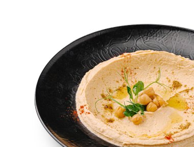 Humus siyah bir tabakta sunulur, nohut, bitki ve zeytinyağı ile süslenir. Çanak pürüzsüz bir doku ve davetkar renkler sergiliyor, tazeliğini vurguluyor..