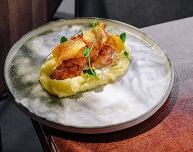 Taze otlar ve çıtır patates cipsleriyle süslenmiş, kremalı patates püresi üzerindeki yumuşak tavuğun sunduğu güzel bir yemek. Zarif kaplama mutfak sanatını ön plana çıkarıyor..