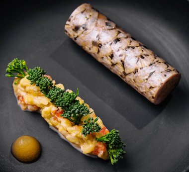 Bu gurme tabağında sanatsal bir et, taze brokoli ve koyu bir tabakta lezzetli bir sos sergileniyor. Mutfak yaratıcılığı ve detaylara dikkat çekiliyor..