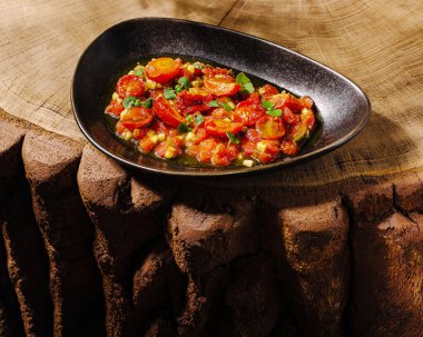 Pişmiş domates ve karışık sebzelerden oluşan canlı bir yemek şık bir kasede servis edilir..