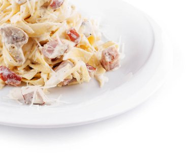 Lezzetli bir kremalı makarna tabağında kızarmış pastırma ve peynirli fettuccine bulunur. Basit beyaz bir tabakta sunuluyor. Lezzetli malzemelerini sergiliyor..