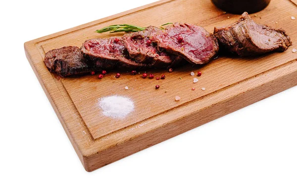 İnce dilimlenmiş biftek ahşap bir tahtanın üzerinde, otlarla süslenmiş ve küçük bir tabak sosla süslenmiş. Bu yemek güzel yemekler ve iyi pişmiş etler için ideal..