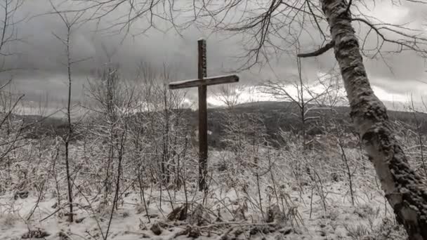 Kreuz in den Bergen im Winter. Zeitraffer. die Sonne scheint durch die Wolken. — Stockvideo