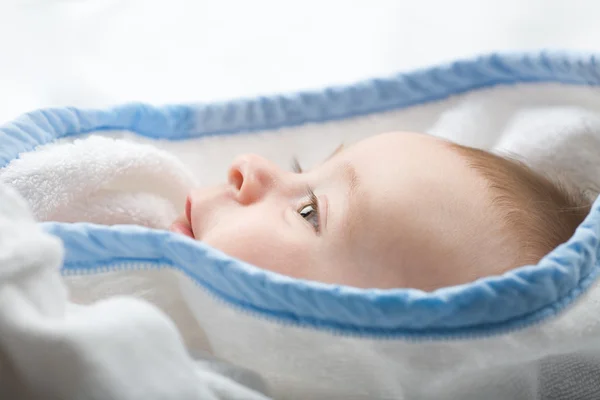 Mooie kleine baby met grote ogen witte handdoek op zoek naar iets in — Stockfoto