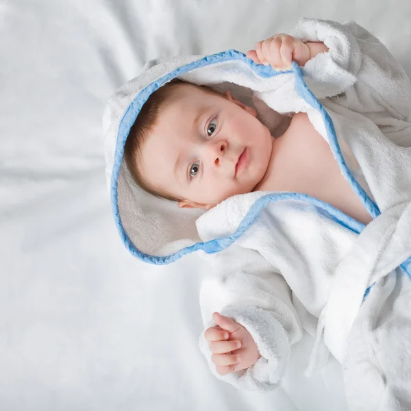 Mooie kleine baby met grote ogen in witte handdoek camera kijken — Stockfoto