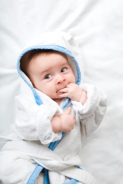 Красива маленька дитина з великими очима в білому рушнику кусає руку — стокове фото