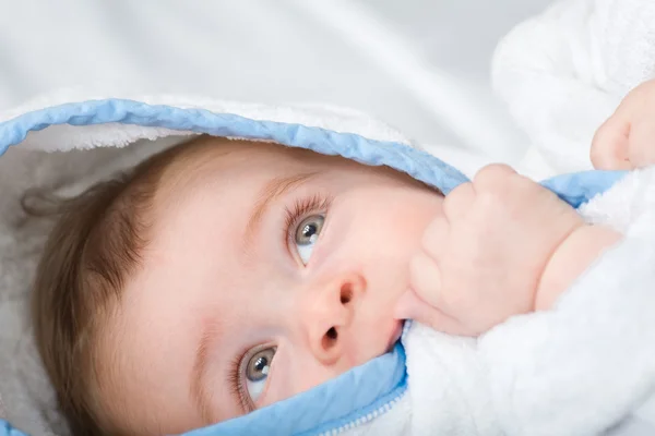 Mooie kleine baby met grote ogen witte handdoek in zijn hand bijten — Stockfoto