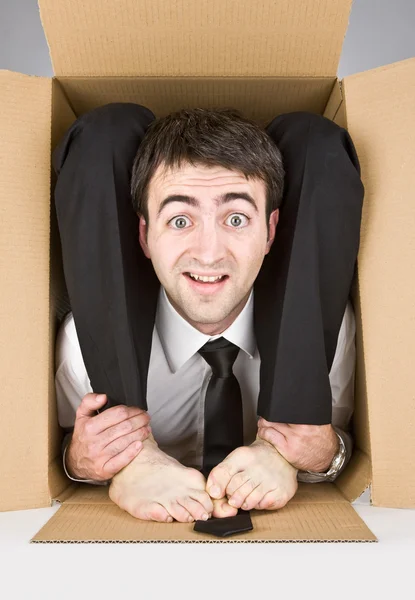 Rugalmas üzletember, a kétes mosolygó szembenéz egy karton dobozban — Stock Fotó