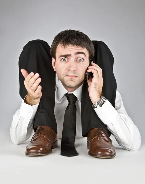 Homem de negócios flexível com rosto duvidoso falando no telefone isolado no branco — Fotografia de Stock
