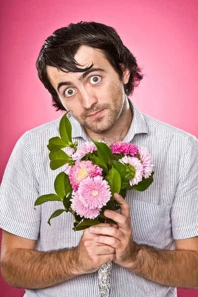 Funny psychopathic nerd with flowers isolated on pink — Stock Photo, Image