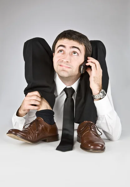 Homem de negócios flexível com rosto duvidoso isolado em branco falando ao telefone — Fotografia de Stock