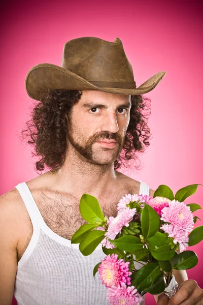 Vaquero desgastado con bigote, flores y sombrero retrato aislado en rosa — Foto de Stock