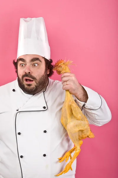Сумасшедший шеф-повар слушает курицу, изолированную на розовый — стоковое фото