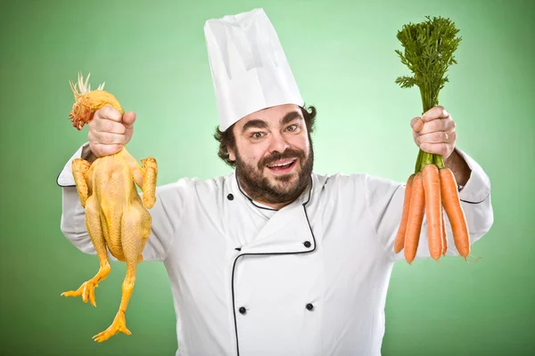 Улыбаясь и дикий шеф-повар показать овощи и курицу изолированы на зеленый — стоковое фото