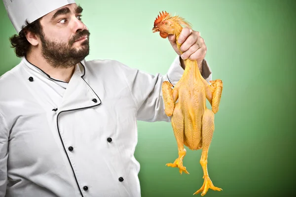 Cozinheiro chef duvidoso e mostrar frango isolado no verde — Fotografia de Stock