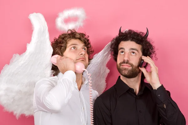 Engraçado anjo branco e preto diabo falando no telefone isolado em rosa — Fotografia de Stock