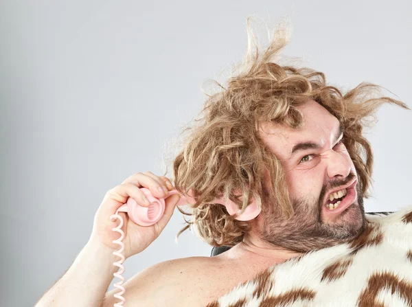 Lelijke onbeleefd prehistorische man met telefoon in zijn haar — Stockfoto