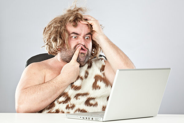 ugly doubtful prehistoric man on laptop