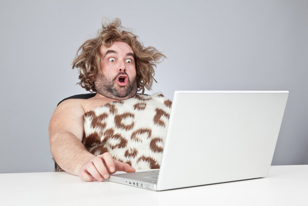 funny perplex prehistoric man using laptop