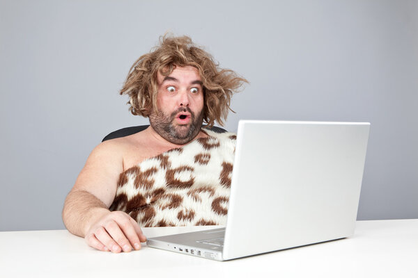 funny perplex prehistoric man using laptop