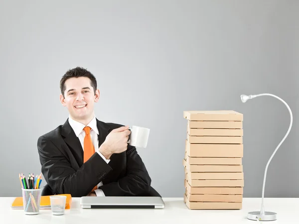 Homem de negócios descontraído com xícara de café e laptop na mesa isolado em cinza — Fotografia de Stock