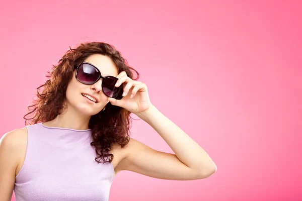 Hermosa chica rizada joven con gafas de sol retrato aislado en rosa — Foto de Stock