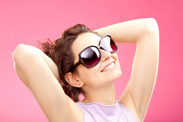Mooie gekrulde meisje met zonnebril portret geïsoleerd op roze — Stockfoto