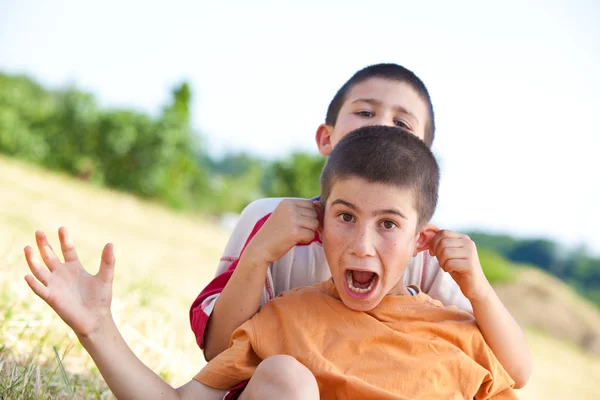 Hermoso divertido jóvenes sonrientes hermanos jugar al aire libre en el campo —  Fotos de Stock